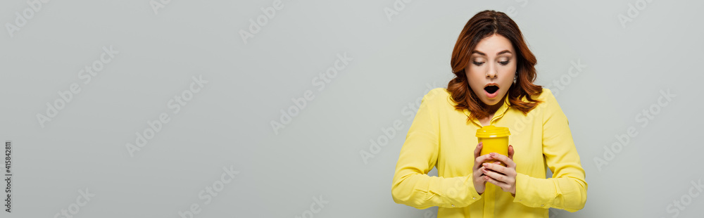 shocked woman holding hot takeaway drink on grey, banner shocked woman holding hot takeaway drink on grey, banner