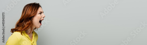 angry woman screaming while looking away on grey, banner photo