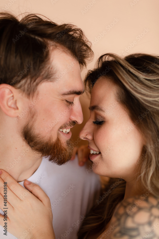 Portrait of a man and woman in an embrace on beige background. Couple smiling. Portrait of a man and woman in an embrace on beige background. Couple smiling.