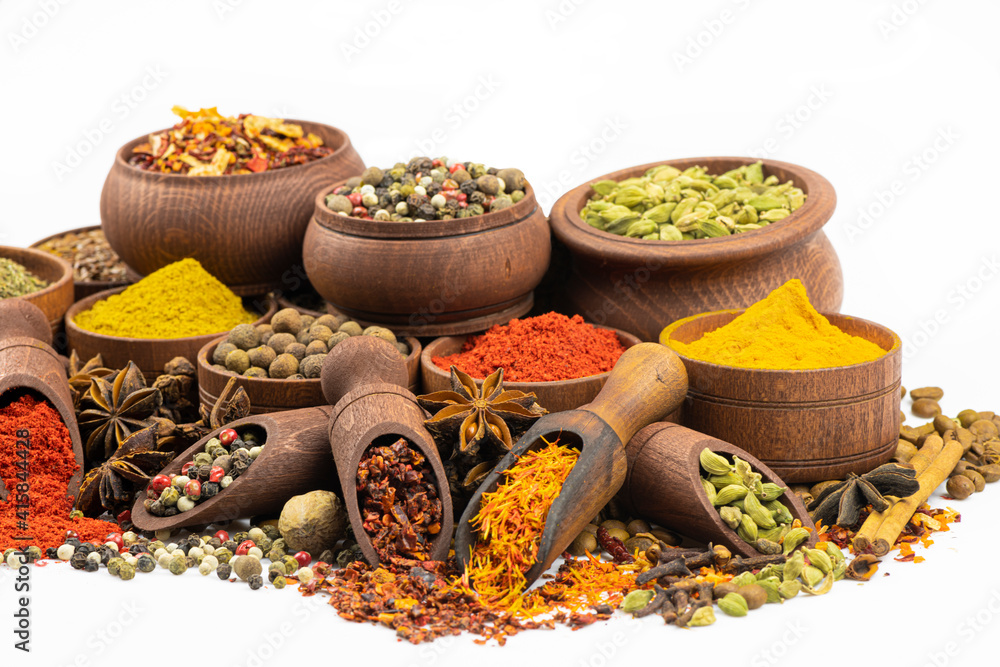 Assortment of spices  to wooden tableware by close up on a white background.