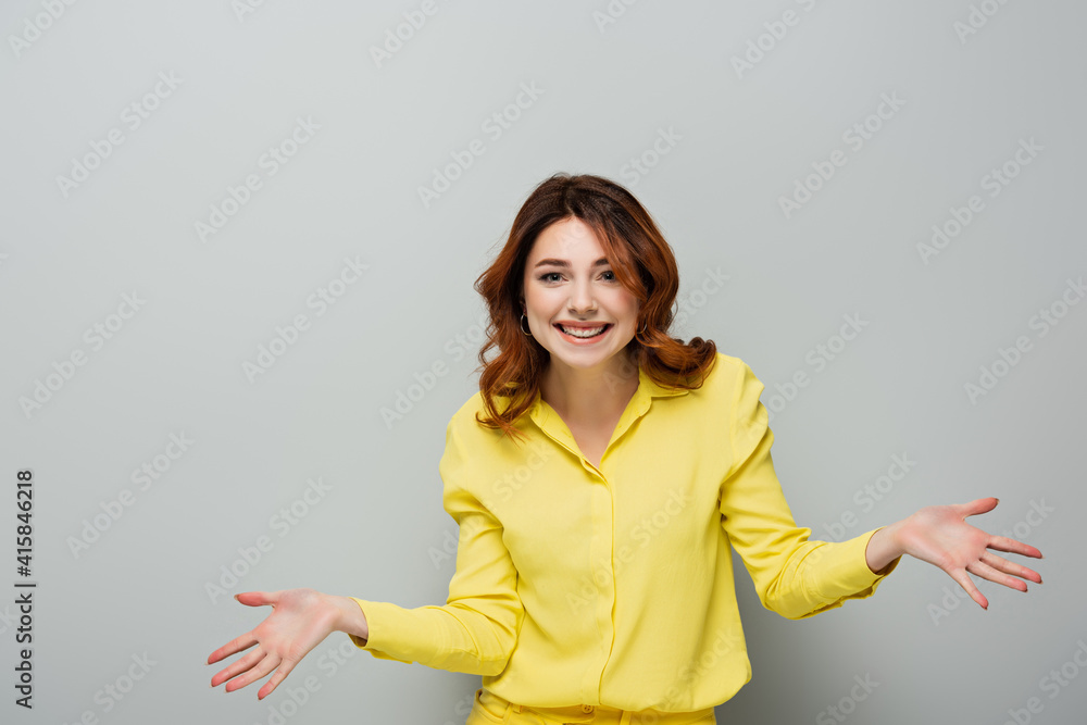 cheerful woman looking at camera while standing with open arms on grey cheerful woman looking at camera while standing with open arms on grey