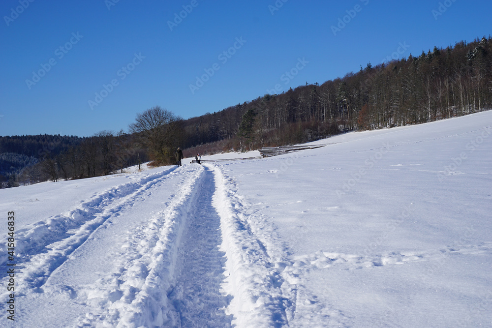 Traktorspuren im hohen Schnee als Spuren zum Wandern oder Spazierengehen 