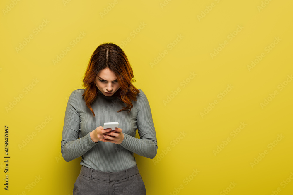 young woman with curly hair messaging on mobile phone on yellow young woman with curly hair messaging on mobile phone on yellow
