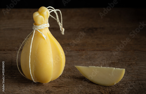 Head and slice of typical Italian cheese Caciocavallo on a wooden surface.. photo