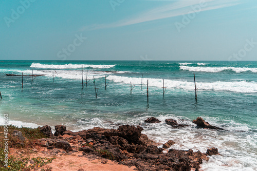 Tropikalna pla  a z palmami  niebieski ocean z falami oraz kije rybackie.