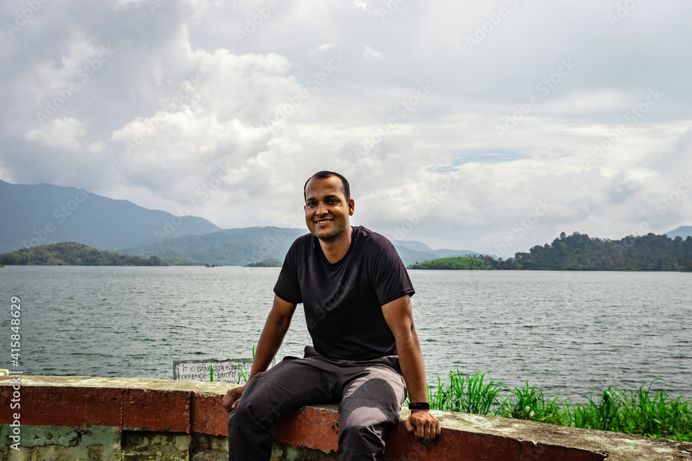 man smiling at pristine lake with mountain background
