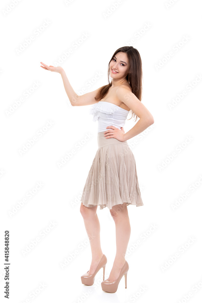 Pleasing smiling young woman looking at camera and pointing at copy space where an advertising message can be written, isolated on white background. Pleasing smiling young woman looking at camera and pointing at copy space where an advertising message can be written, isolated on white background.