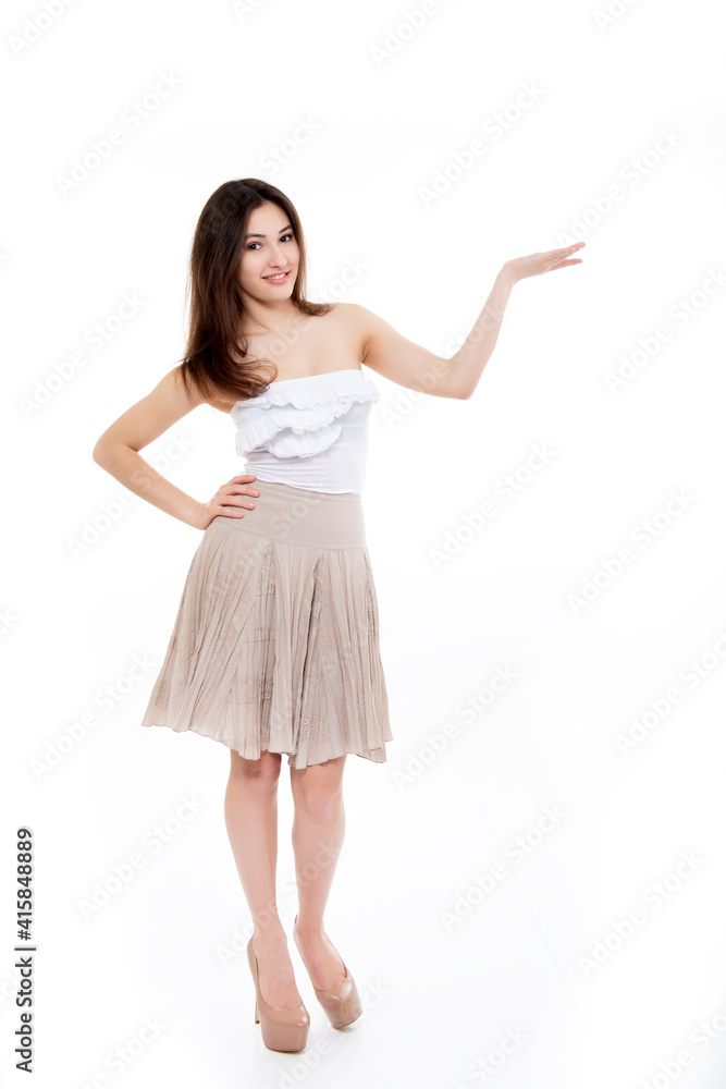 Pleasing smiling young woman looking at camera and pointing at copy space where an advertising message can be written, isolated on white background. Pleasing smiling young woman looking at camera and pointing at copy space where an advertising message can be written, isolated on white background.