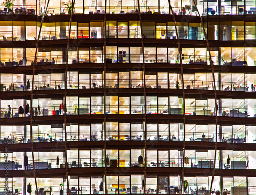 outside façade of a building w/ clear windows showing offices inside the building.