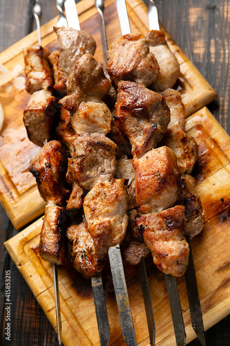 kebabs meat on metal skewer on cutting board rustic style