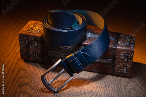 Men's belt, blue, on a rectangular vase, on an oak table top