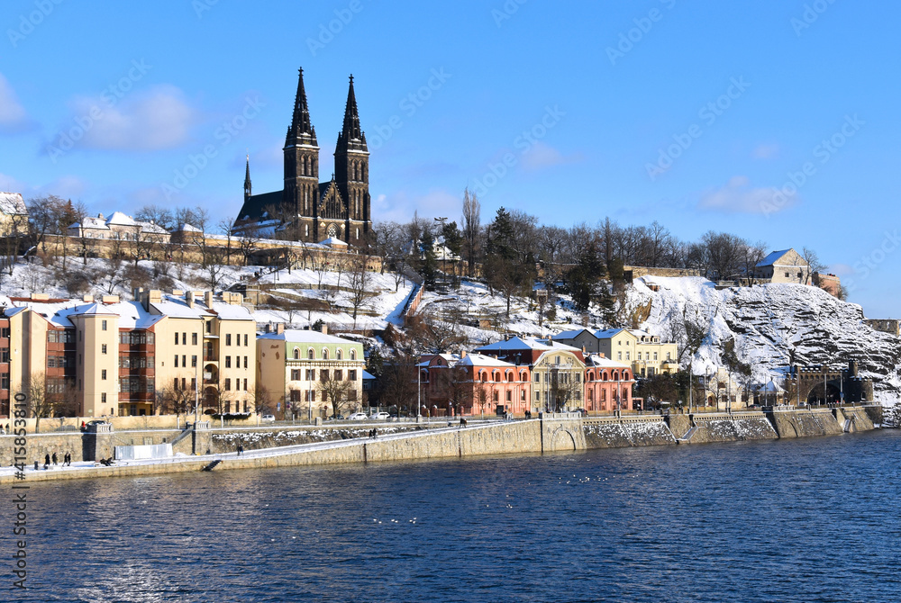 Fototapeta premium Prague Czech Republic snowy Vysehrad and Vltava river stock images. Winter in Prague city stock photo. Vysehrad church during winter time images. Basilica of St. Peter and Paul in Prague at Vyšehrad