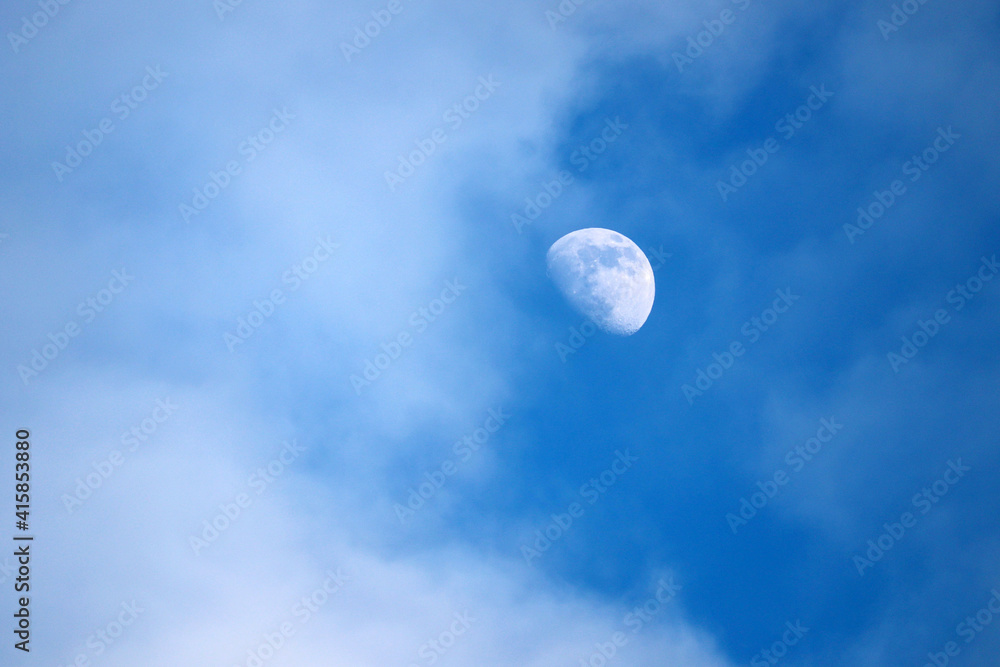 Rising moon in blue sky with white clouds Rising moon in blue sky with white clouds