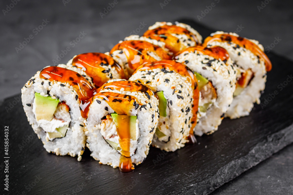 appetizing sushi roll california with eel avocado cucumber and sesame seeds on a black stone plate appetizing sushi roll california with eel avocado cucumber and sesame seeds on a black stone plate