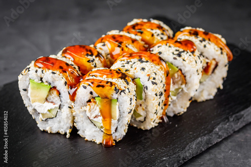 appetizing sushi roll california with eel avocado cucumber and sesame seeds on a black stone plate