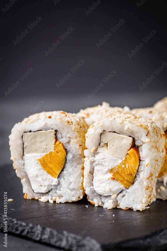 appetizing sushi roll california with tofu cheese and omelet on a black stone plate appetizing sushi roll california with tofu cheese and omelet on a black stone plate