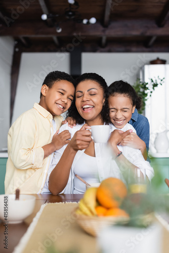 laughing african american woman near happy children on blurred foreground