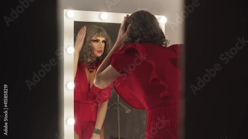A young man drag artist preening up in front of the mirror 