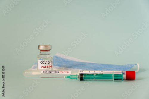 Coronavirus COVID-19 injection, vaccine in a small bottle with doctor mask against the virus and PCR test