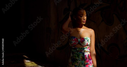 A woman walks from the light of the sun rays into the drkness of an abandoned warehouse photo