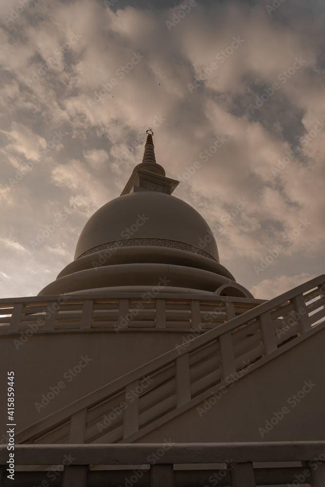 Piękna biała stupa, pagoda w świątynni buddyjskiej na tle nieba i zachodzącego słońca.