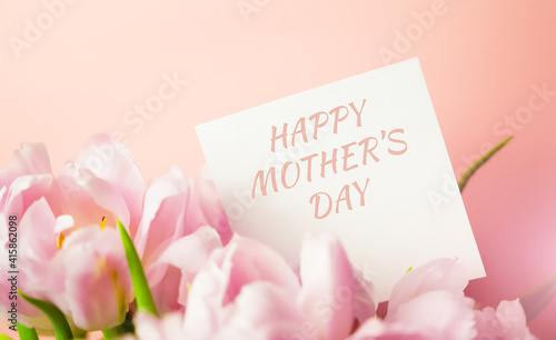 A note with HAPPY MOTHER'S DAY text hidden in a bunch of pink tulips. Postcard