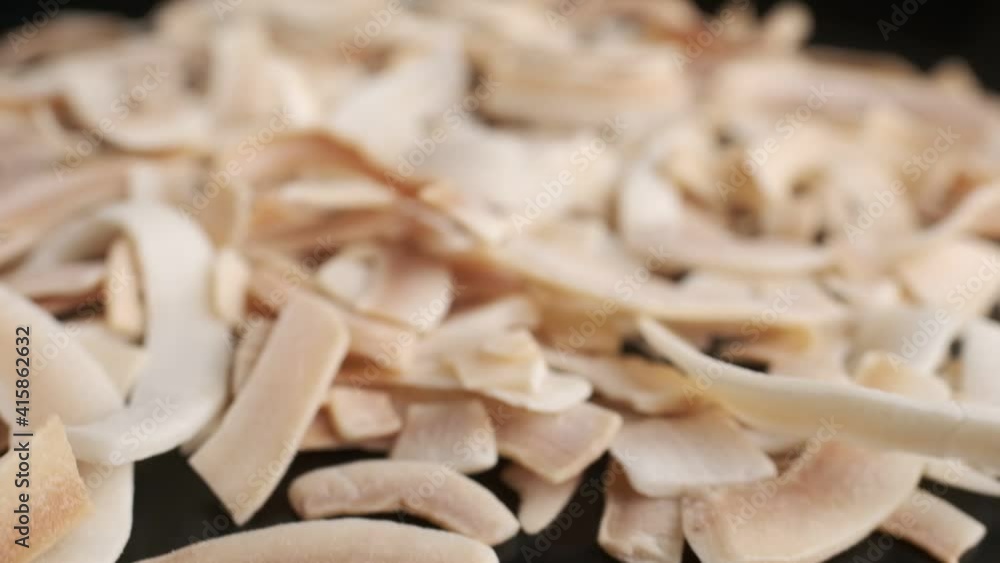 Coconut chips on a dark table close-up. Black background, slow motion. Coconut chips on a dark table close-up. Black background, slow motion.