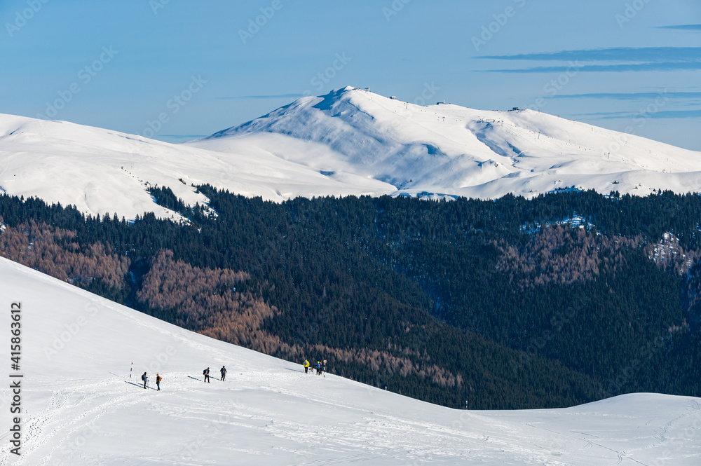 Group of young people hiking in snowy Romanian mountains during a sunny winter day
