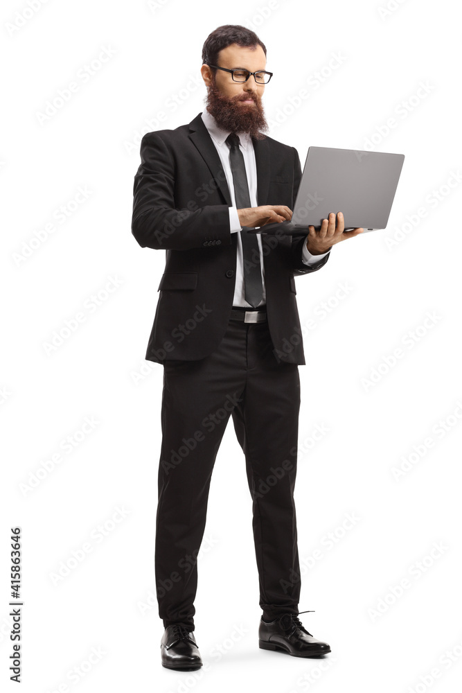 Full length portrait of a bearded man in a suit standing and using a laptop computer Full length portrait of a bearded man in a suit standing and using a laptop computer