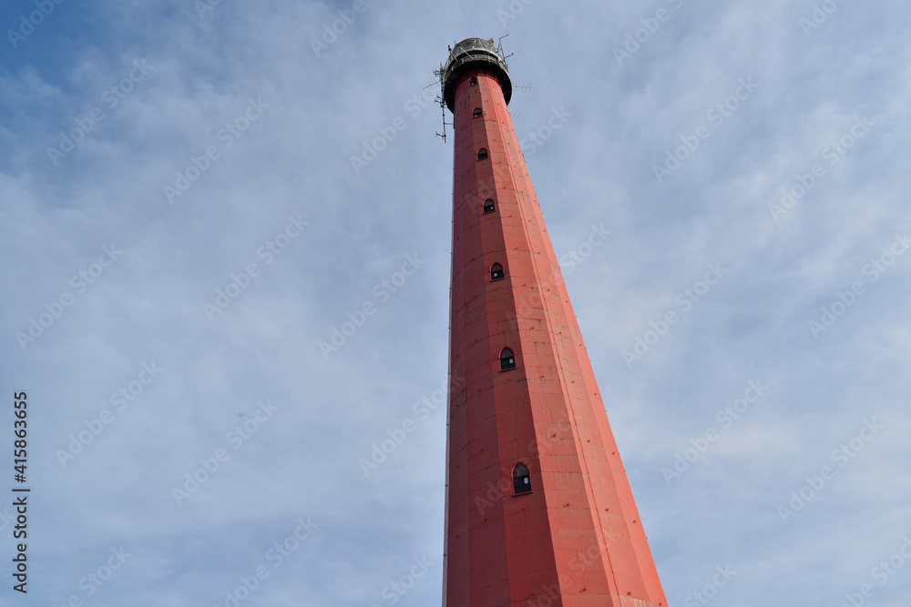A tall red lighthouse reaching for the sky at Atlantikwall, Netherlands