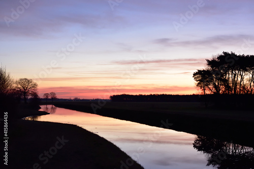 Stunning sunrise reflecting in the water of a canal close to Vinkel in the Netherlands