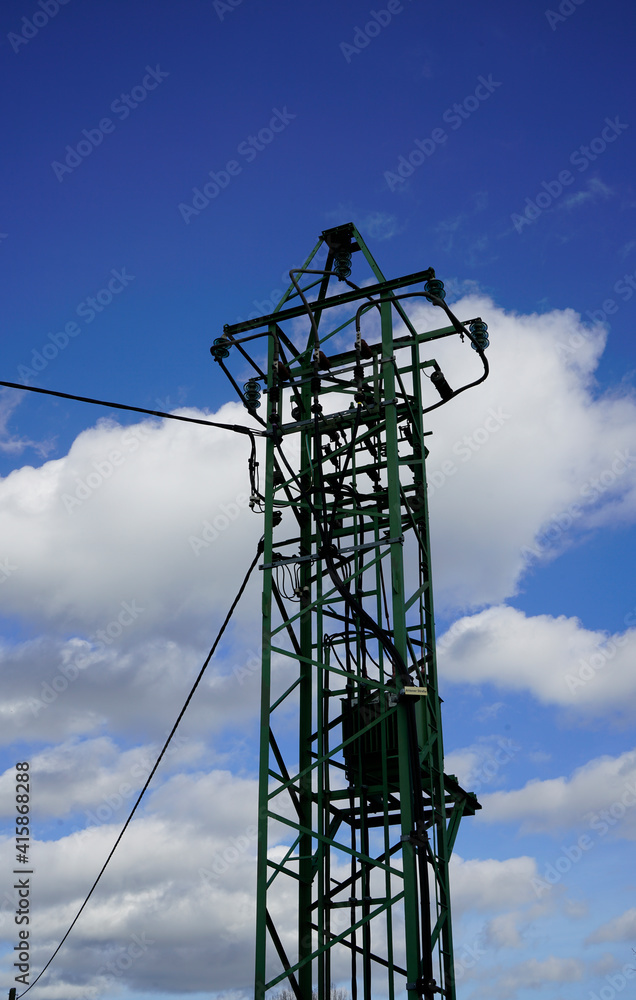Strommast mit blauem Himmel und weißen Wolken im Hintergrund. Überirdische Stromleitung.