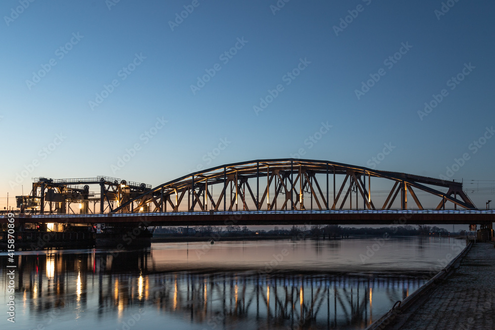Dutch blue illuminated bridge, IJsselspoorbridge (Zutphen) over the high water of the river 'de ijssel'.