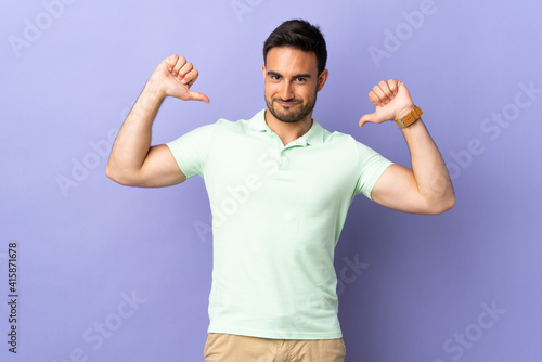Young handsome man isolated on purple background proud and self-satisfied