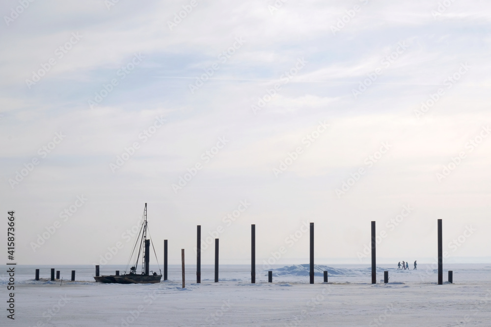 A frozen sea with piles of destroyed pier and boat in morning light. Rzucewo, Puck Bay, Baltic Sea, Poland