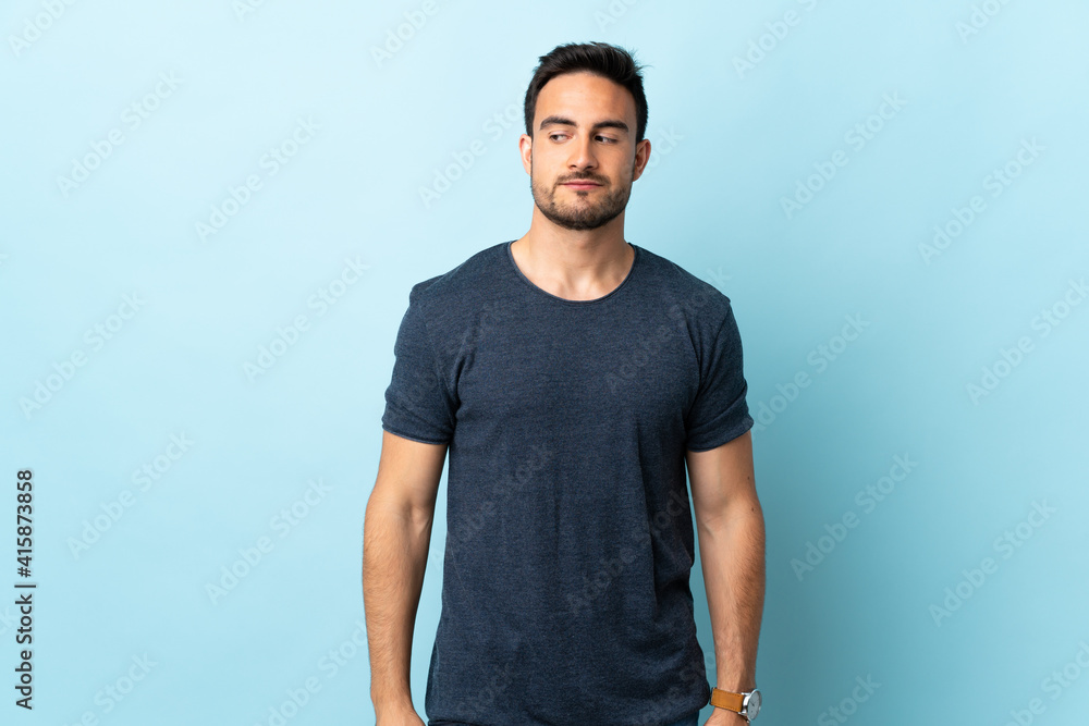 Young handsome man over isolated background having doubts while looking side Young handsome man over isolated background having doubts while looking side