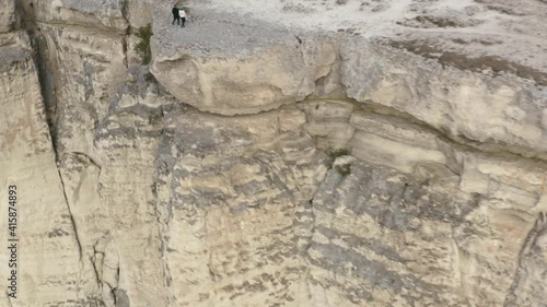 Wallpaper Mural Romantic tourist couple holding hands on cliff edge view from drone above. Traveling couple walking on edge observation deck on mountain summit. Aerial around view 4k. Torontodigital.ca
