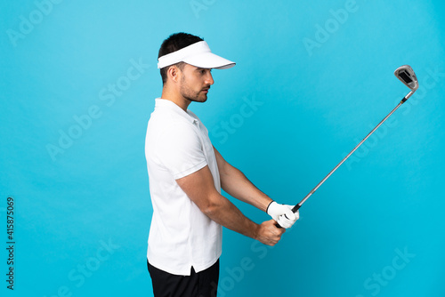Young handsome man isolated on blue background playing golf