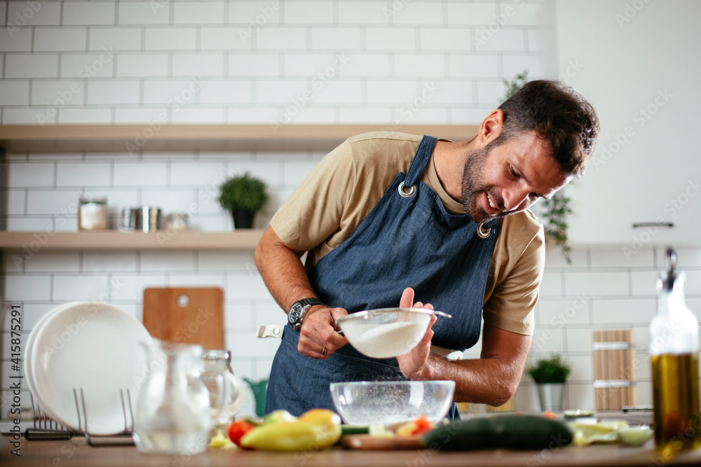 Happy man baking in the kitchen. Man making fresh pasta at home. Happy man baking in the kitchen. Man making fresh pasta at home.