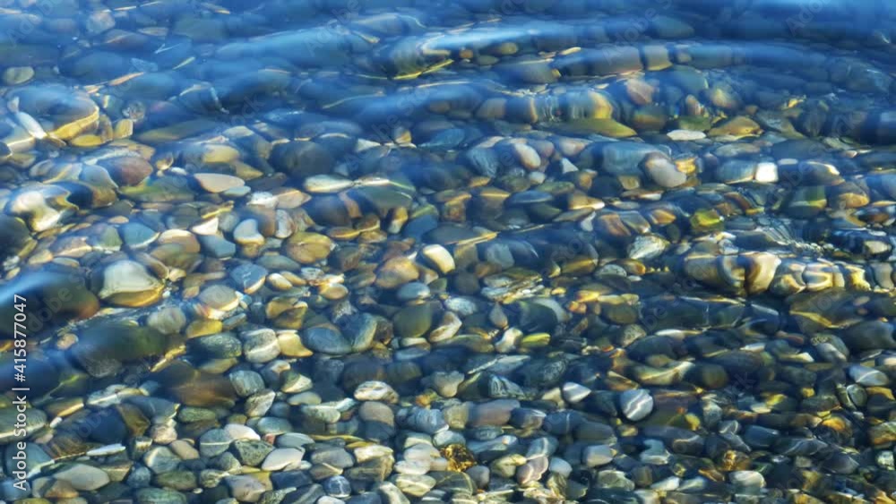 Reflets de lumière par des vagues sur des pierres