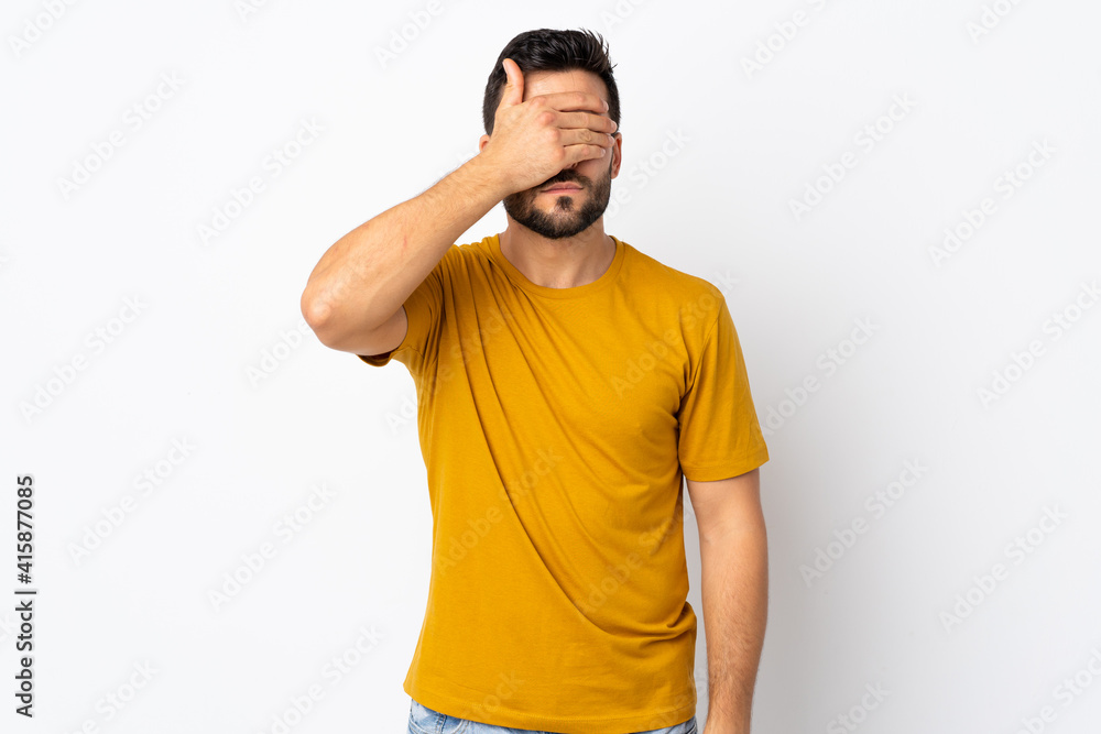 Young handsome man with beard isolated on white background covering eyes by hands. Do not want to see something Young handsome man with beard isolated on white background covering eyes by hands. Do not want to see something