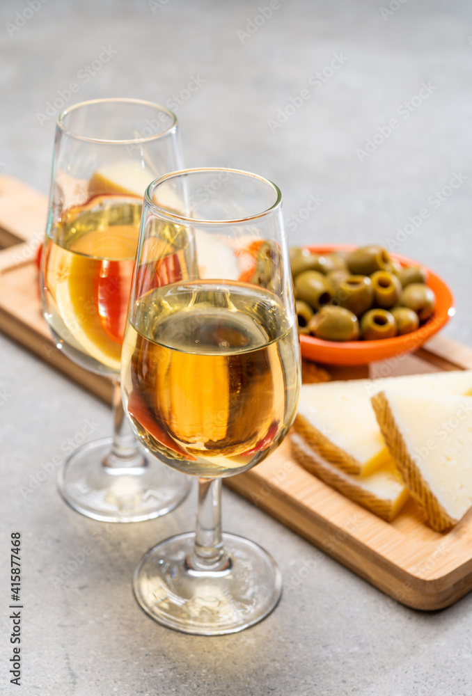 Glasses of dry fino sherry wine served with spanish tapas, manchego cheese, green olives, cheese crackers Glasses of dry fino sherry wine served with spanish tapas, manchego cheese, green olives, cheese crackers