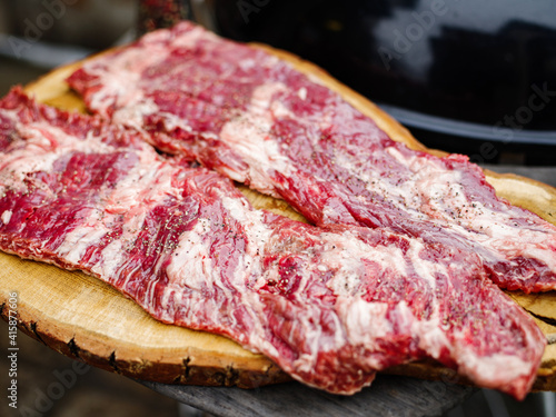 Raw hanging tender or onglet steak of beef on wooden Board. Preparing meat for barbecue grilling. BBQ.