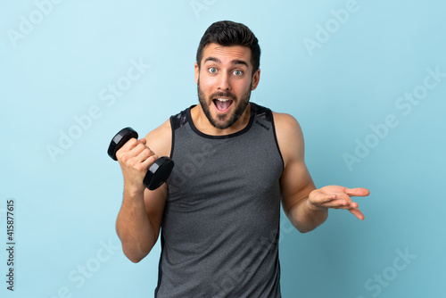 Young sport man with beard making weightlifting with shocked facial expression
