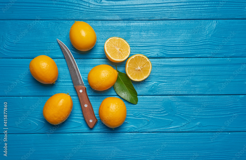 Obraz premium Fresh ripe lemons and knife on blue wooden table. Top view with copy space.