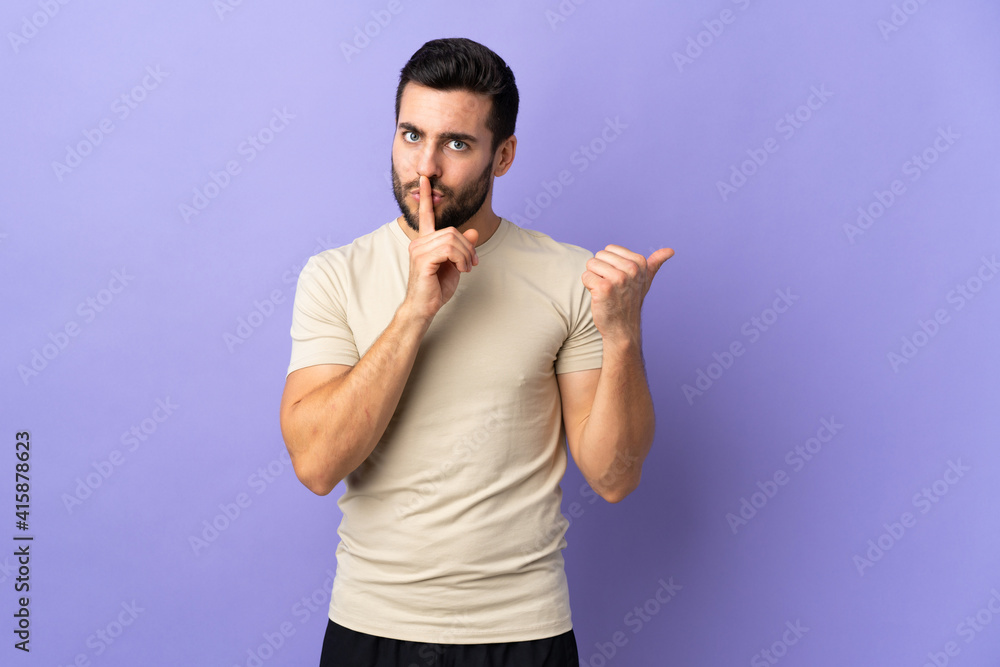 Naklejka premium Young handsome man with beard over isolated background pointing to the side and doing silence gesture
