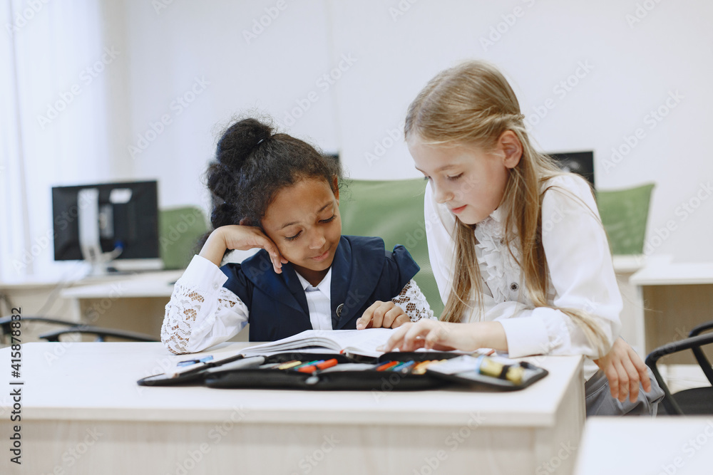 African girl sitting at the table. Schoolgirls read a book during a break. Children sit in a computer science class. African girl sitting at the table. Schoolgirls read a book during a break. Children sit in a computer science class.