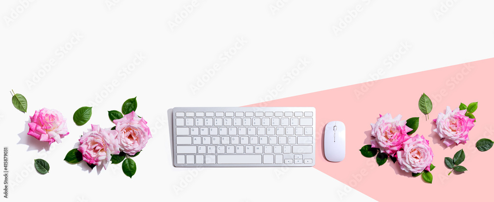 Computer keyboard and a mouse with pink roses - flat lay Computer keyboard and a mouse with pink roses - flat lay