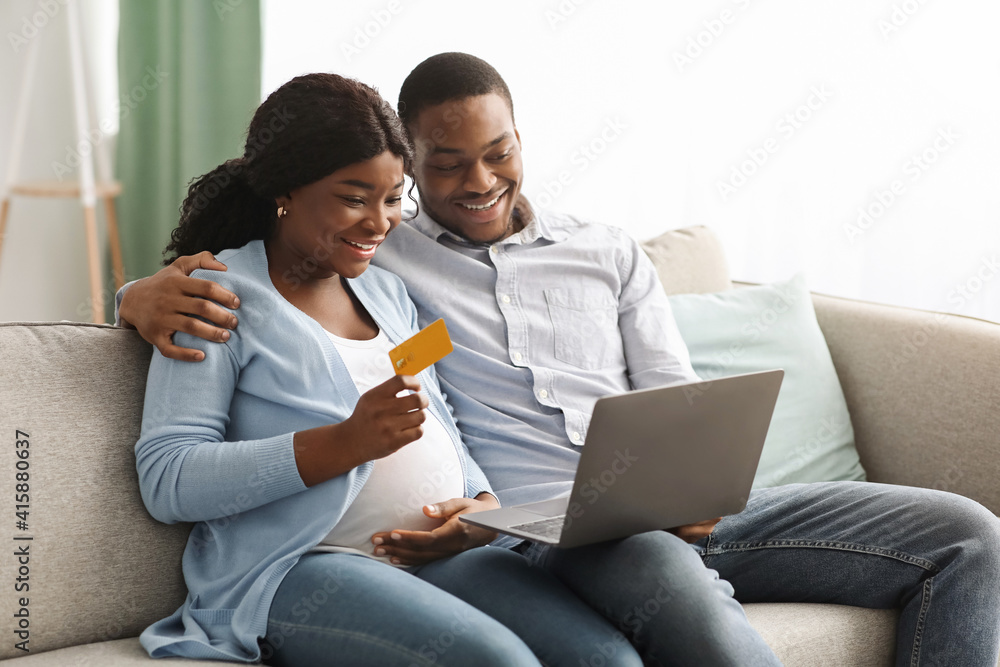 Happy african american expecting family using laptop, shopping online Happy african american expecting family using laptop, shopping online