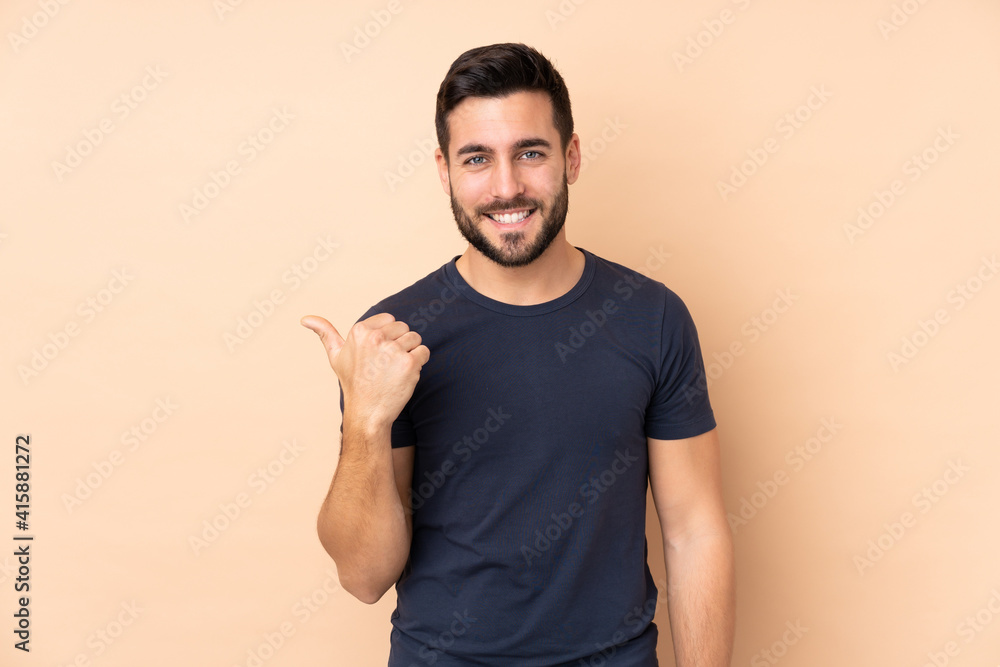 Caucasian handsome man isolated on beige background pointing to the side to present a product Caucasian handsome man isolated on beige background pointing to the side to present a product